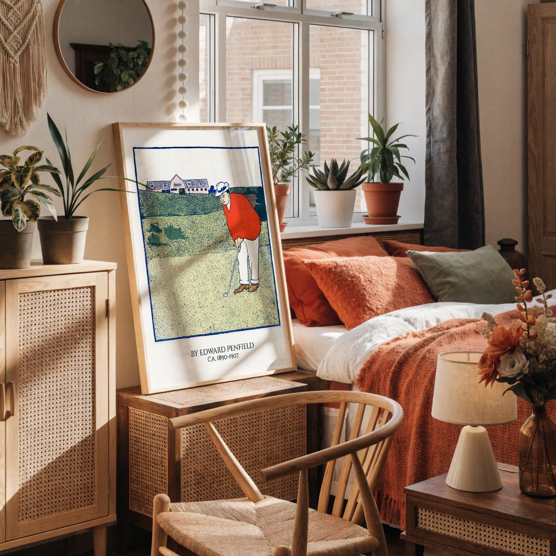 a framed illustration of a golfer on a golf course, with a vase of dried flowers and a cup of coffee on a desk in the foreground.