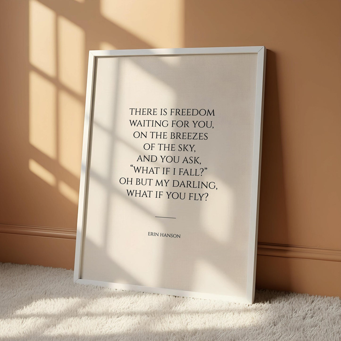a framed quote by Erin Henson, "There is freedom waiting for you on the breezes of the sky, and you ask, 'oh but I fall? 'What if my daring, what if you fly'?" The quote is displayed on a white wall next to a wooden chair, creating a serene and contemplative atmosphere.
