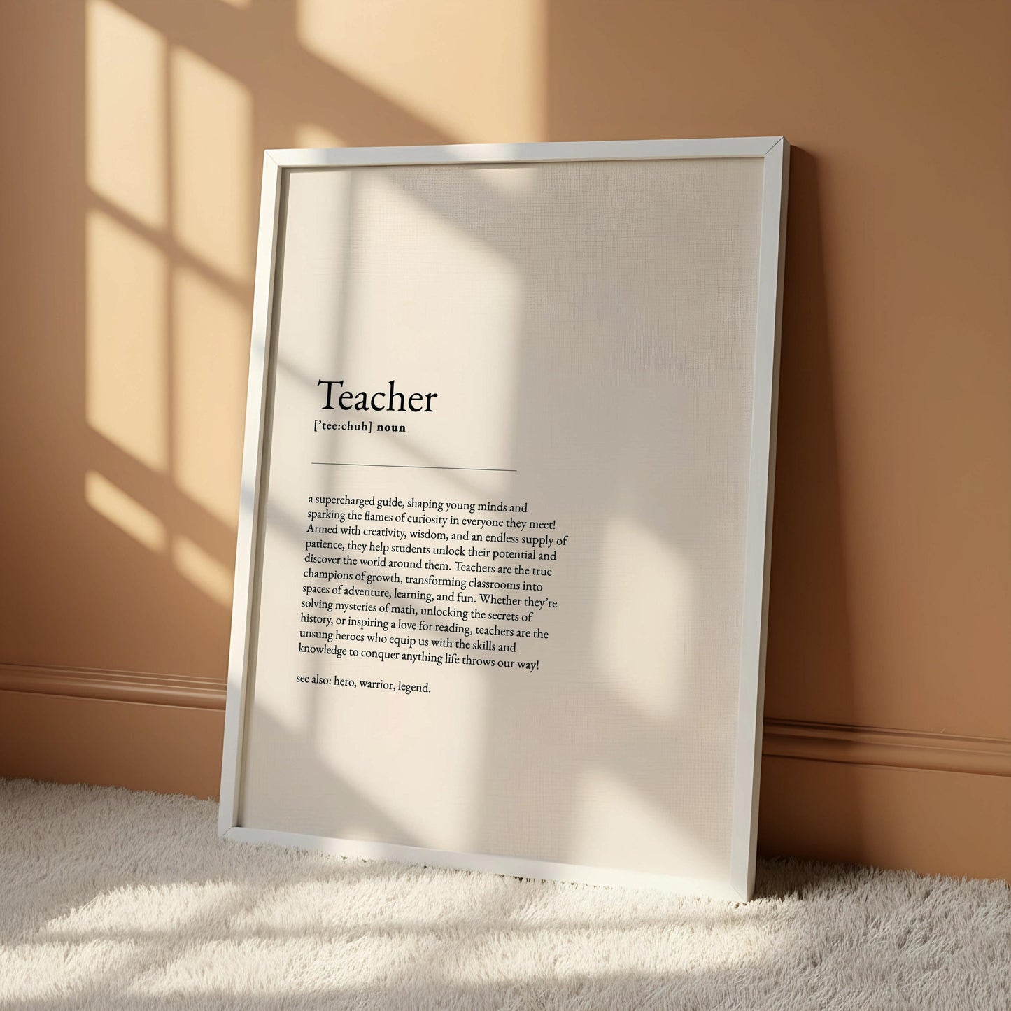 a framed definition of a teacher, a white desk with various items such as a notebook, a cup, a vase with dried flowers, and a mirror.