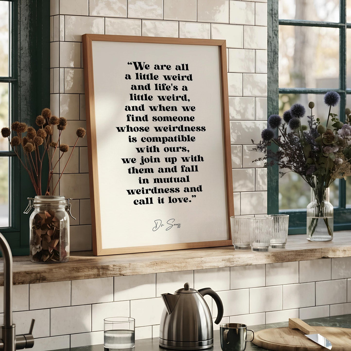 a framed quote by D.S.W. that reads, "We are all a little weird and life's a little weird, and when we find someone whose weirdness is compatible with ours, we join up with them and fall in mutual weirdness and call it love."