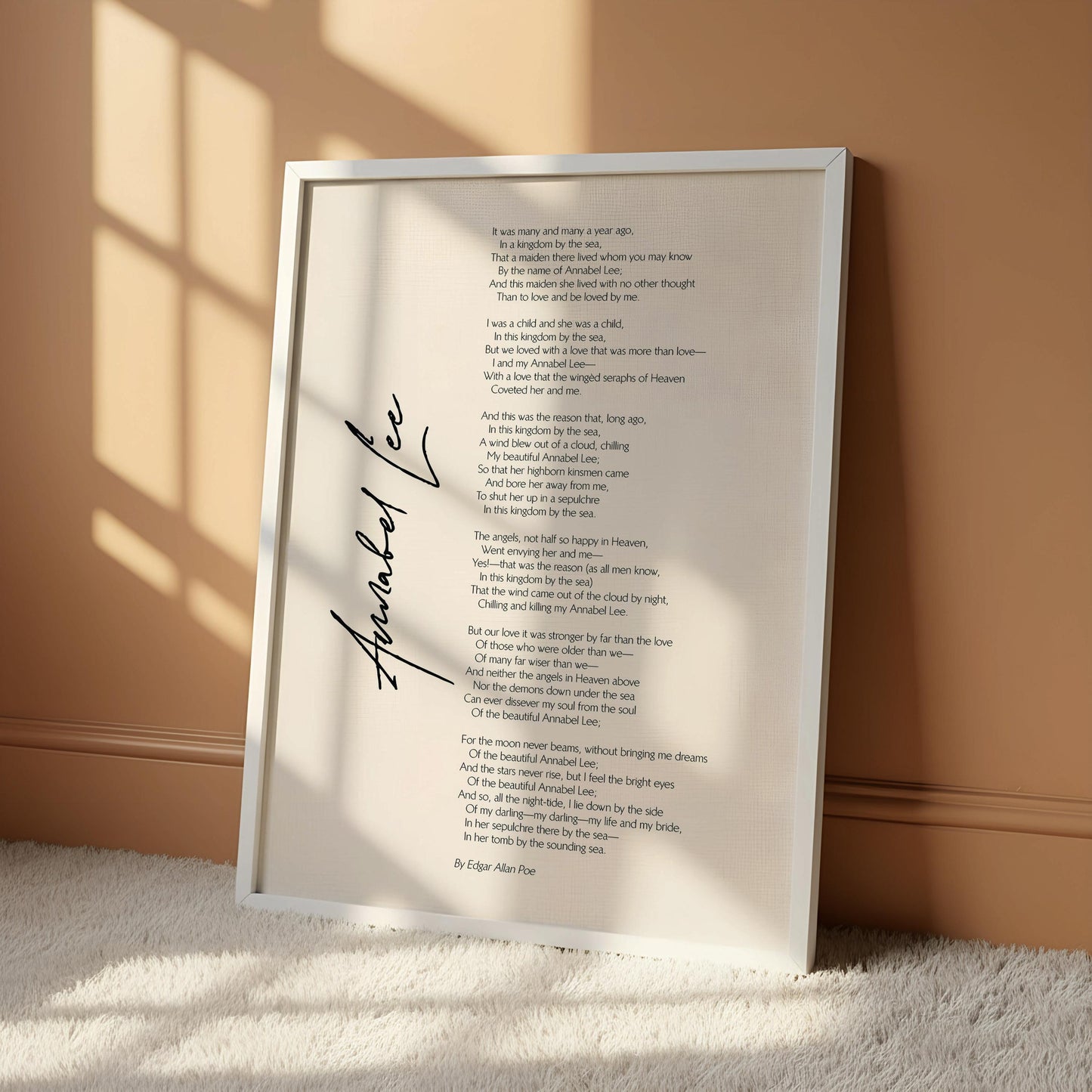 a framed poem titled "Anabel Lee" by Edgar Allan Poe, which is hanging on a wall. The poem is written in a flowing cursive font and is framed by a wooden hanger. The image does not contain any text or additional objects, and the focus is solely on the poem and its presentation.