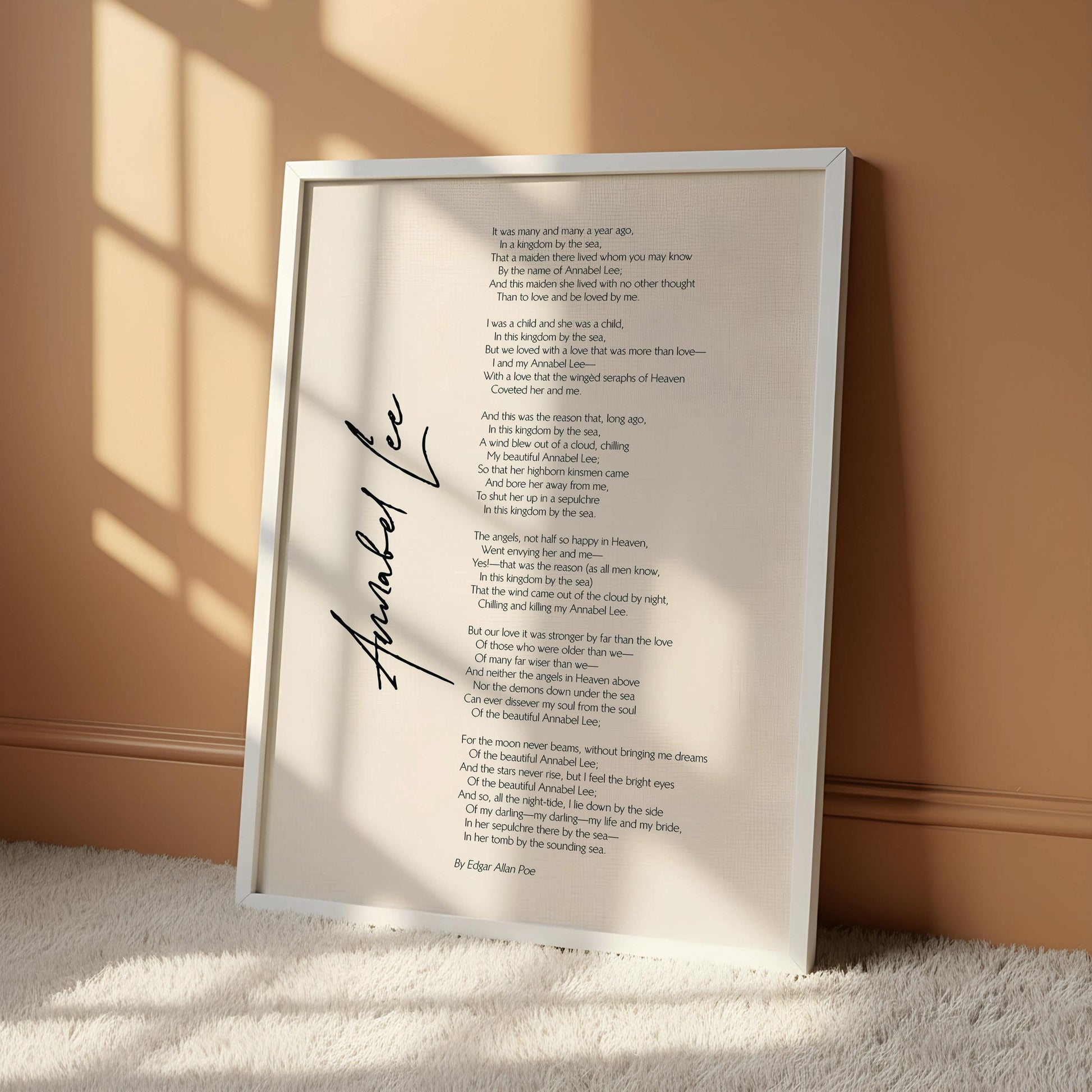 a framed poem titled "Anabel Lee" by Edgar Allan Poe, which is hanging on a wall. The poem is written in a flowing cursive font and is framed by a wooden hanger. The image does not contain any text or additional objects, and the focus is solely on the poem and its presentation.
