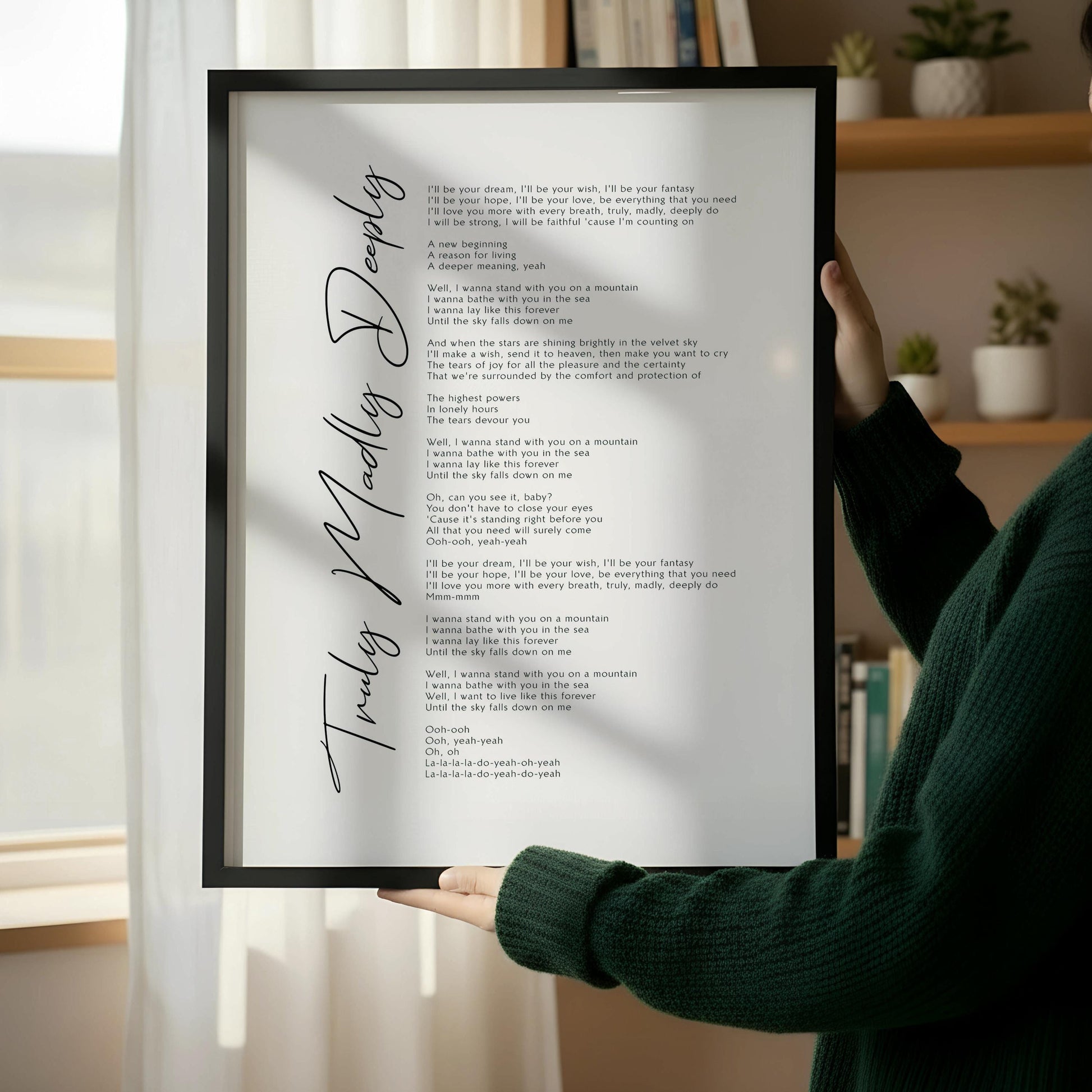 a wooden chair with a stack of books on it, placed against a white wall. There is a framed text or poem on the wall next to the chair.