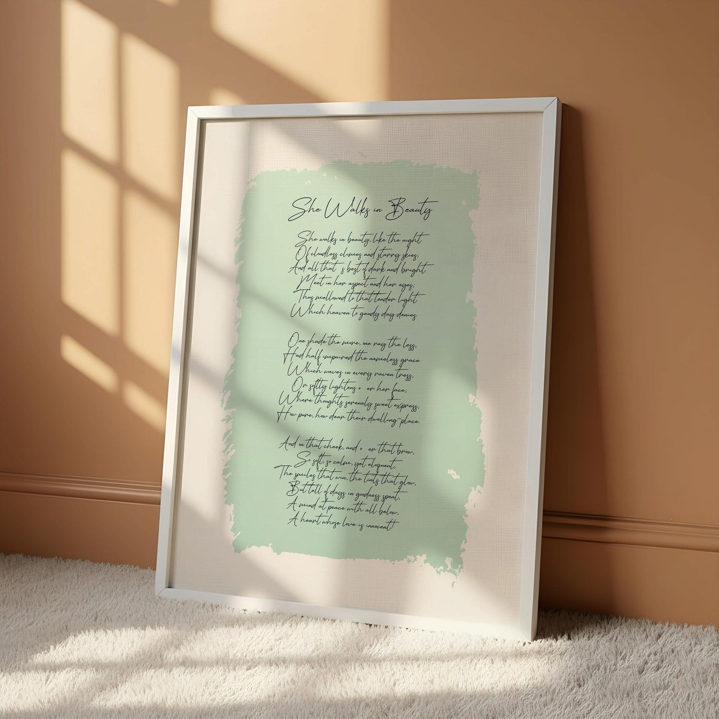 a framed poster with a light blue background and cursive text, hanging on a white wall.