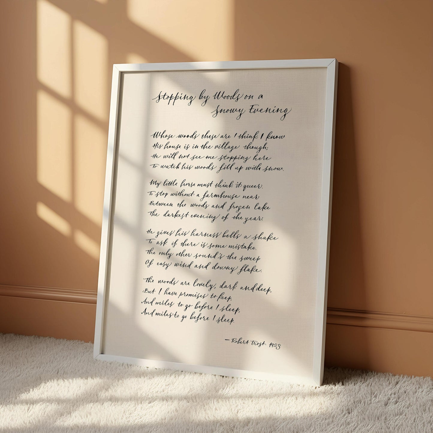 a framed poem titled "Stepping by Woods on a Snowy Evening" by Robert Frost, with a wooden hanger frame.