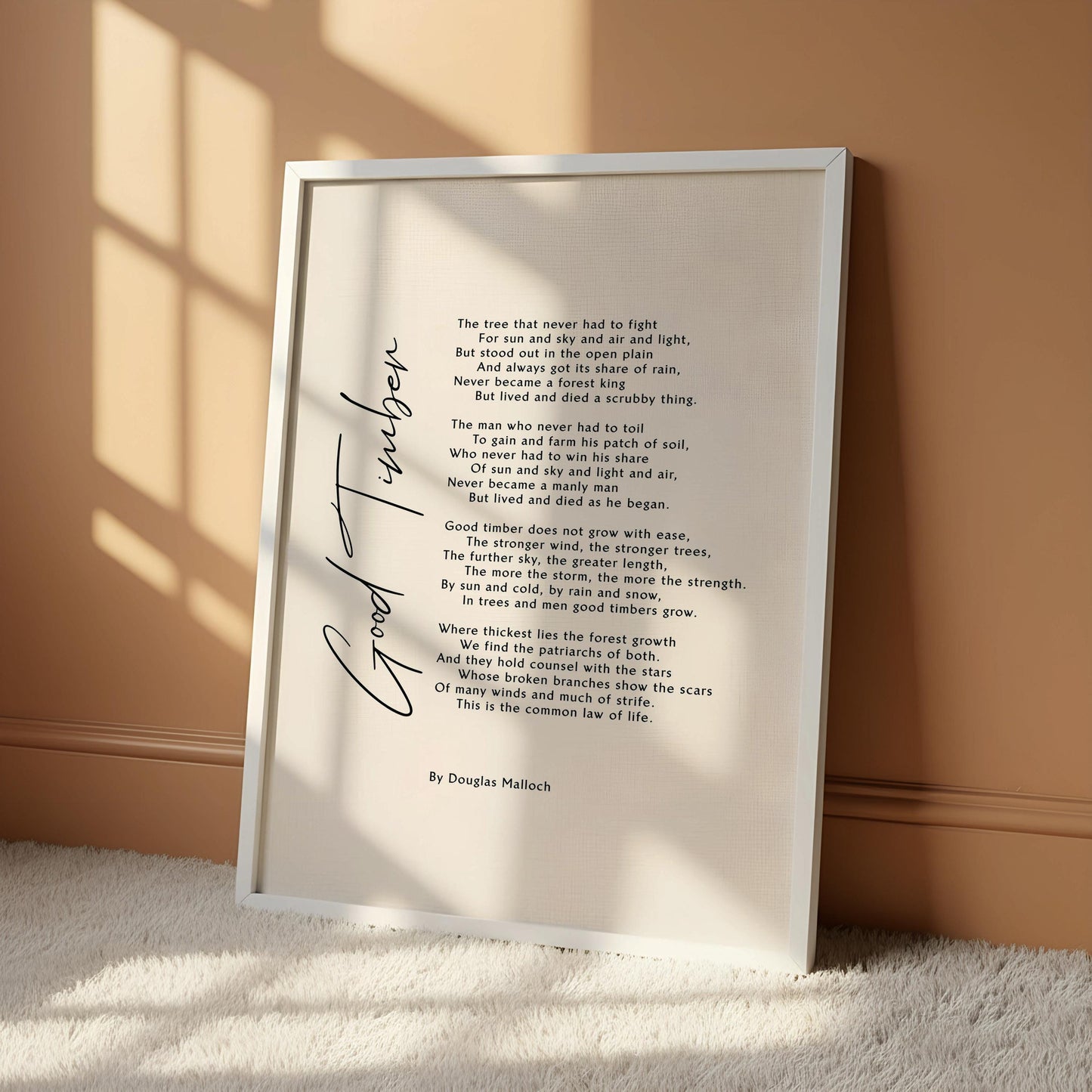 a framed poem titled "Good timber" by Douglas Mallock, which is hung on a wall. The poem is written in a cursive font and features a wooden frame. The text is written in black ink on a white background, and the image includes a blue circle with the text "OAK HANGER FRAME" in the bottom left corner.