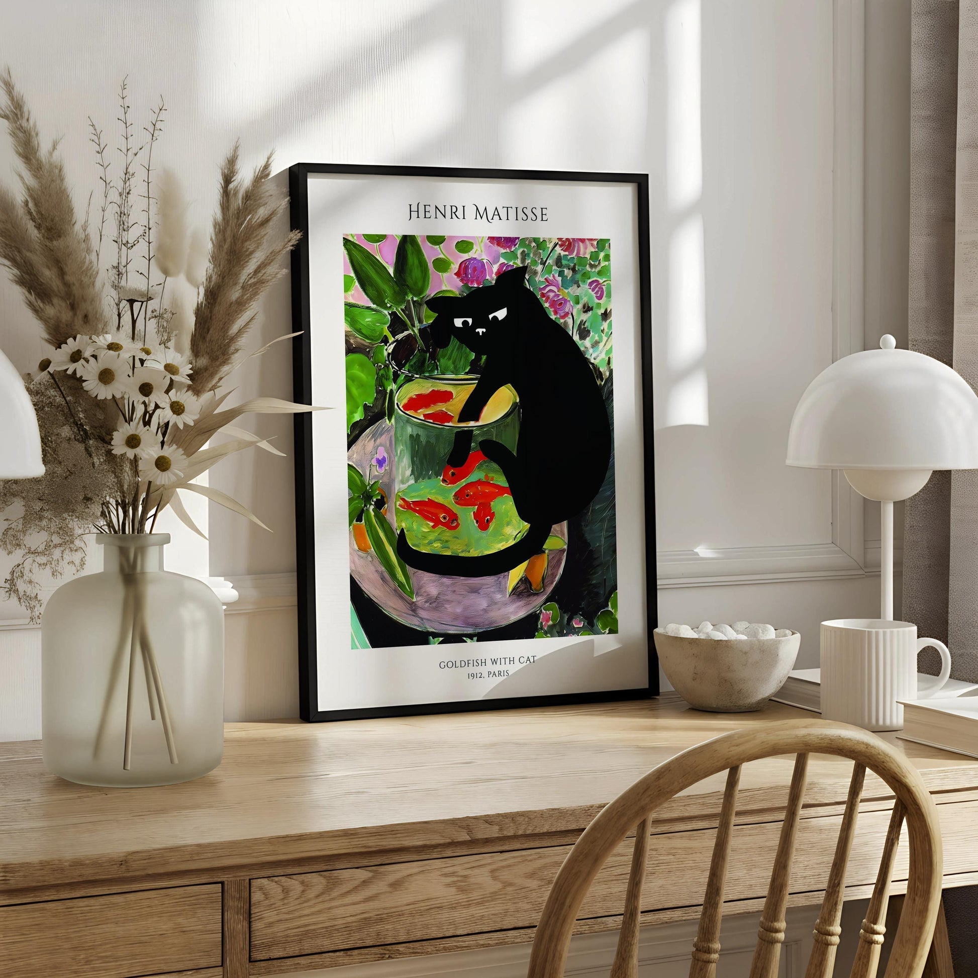A framed painting of a black cat sitting in a glass bowl filled with goldfish, surrounded by colorful flowers and plants.