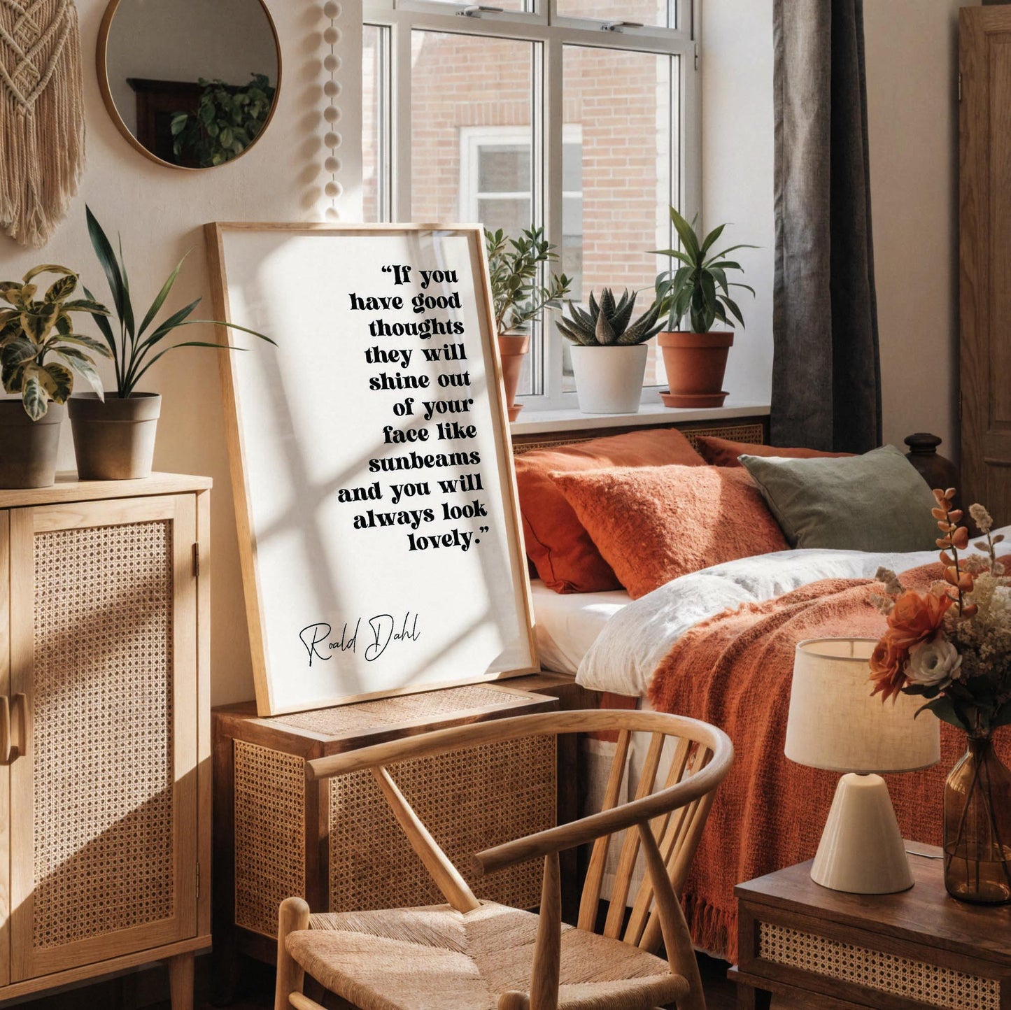 a framed quote by Ralph Dhl on a white wall, accompanied by a white desk with various items such as a notebook, a cup, and a vase with dried flowers.