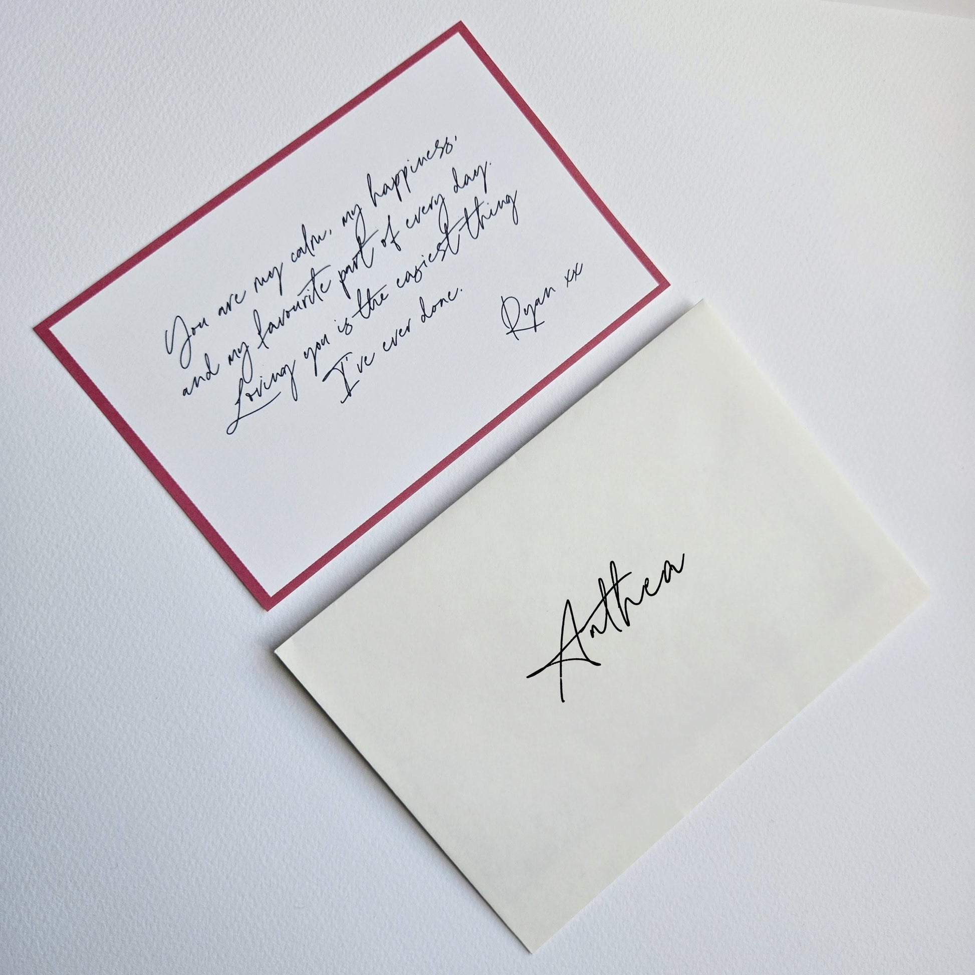 a red and white envelope with a handwritten note inside, placed on a white surface.