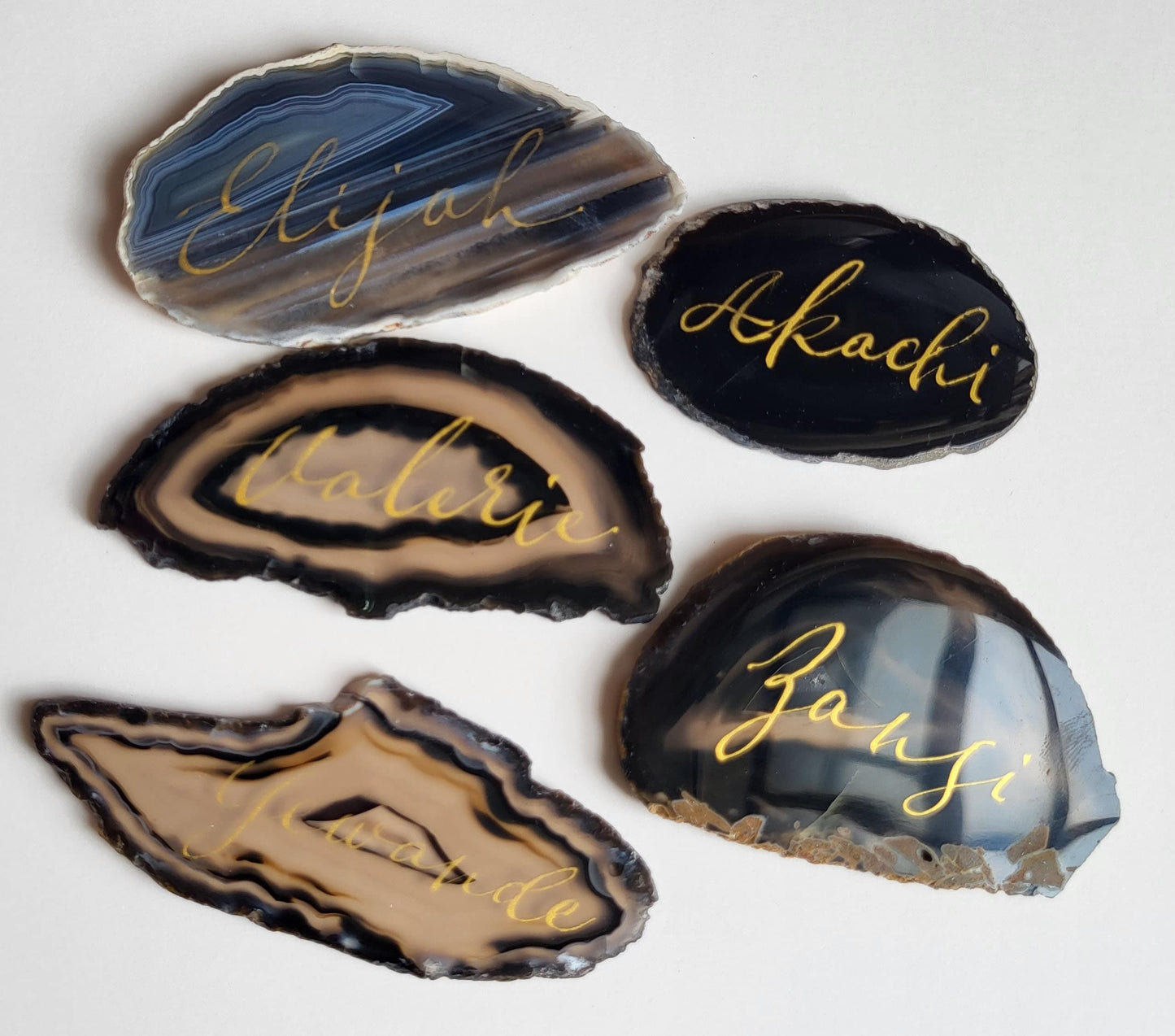 five unique rock slices with names written on them, arranged on a white background.