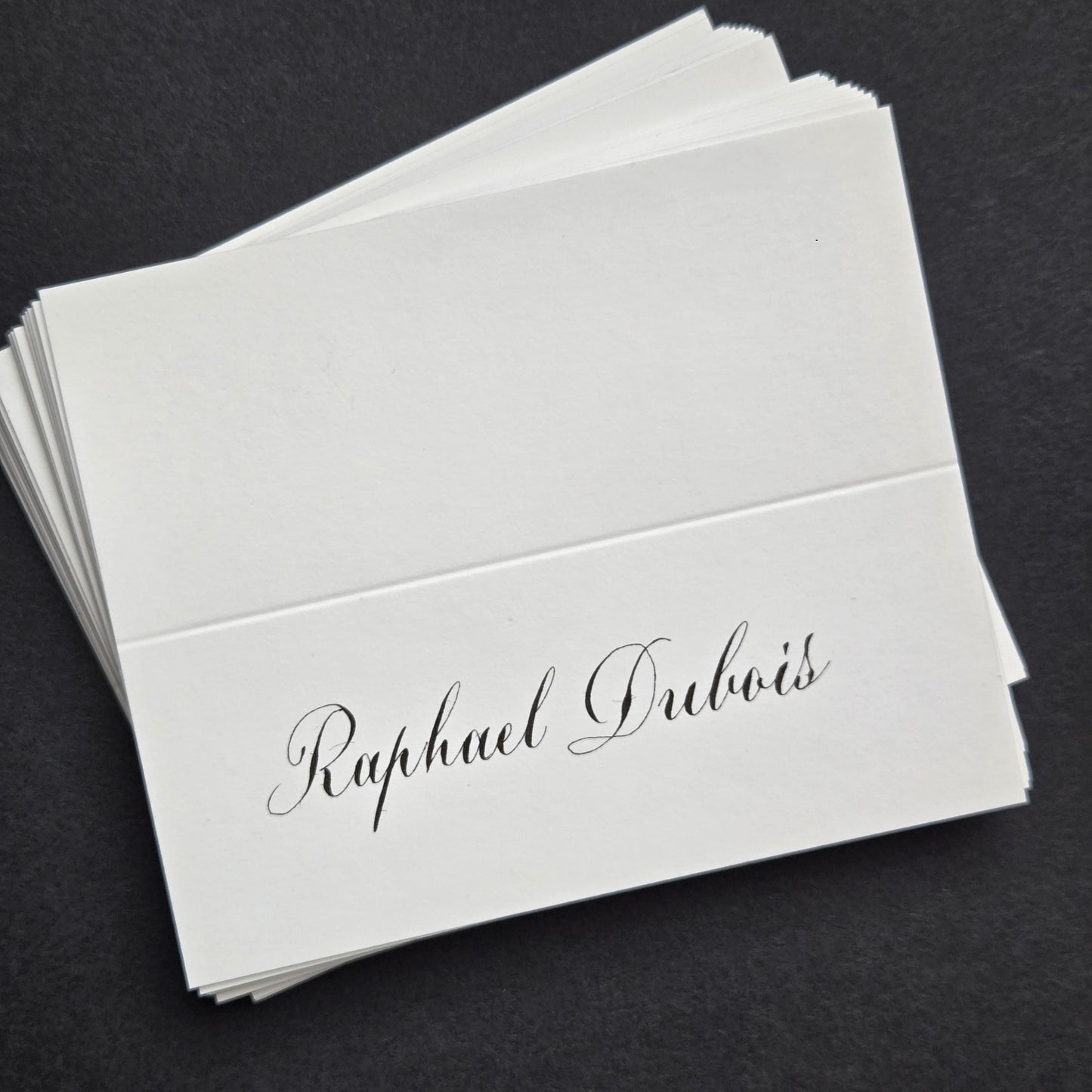 A stack of white business cards with the name "Raphael Dubois" printed on them.