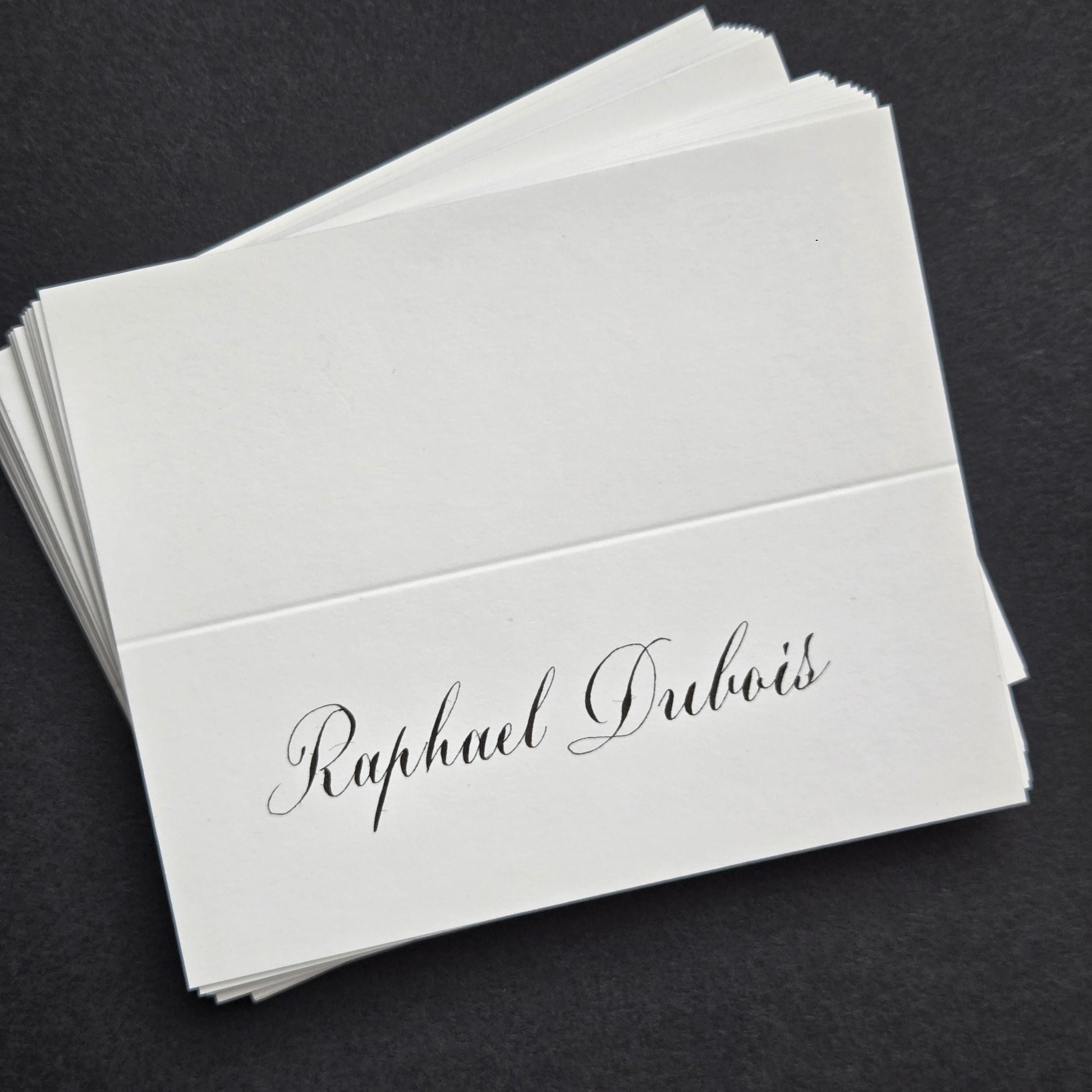 A stack of white business cards with the name "Raphael Dubois" printed on them.