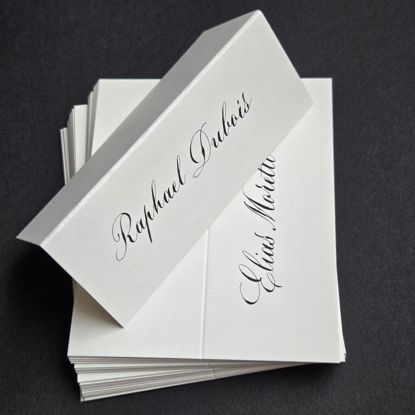 A stack of white paper name cards with elegant cursive text.