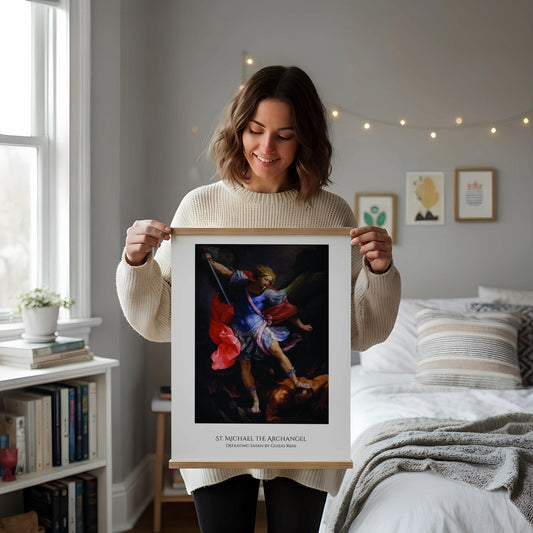 a framed painting of St. Michael the Archangel, a religious figure, standing on a pedestal and holding a sword. The painting is displayed on a wooden floor next to a wooden chair.