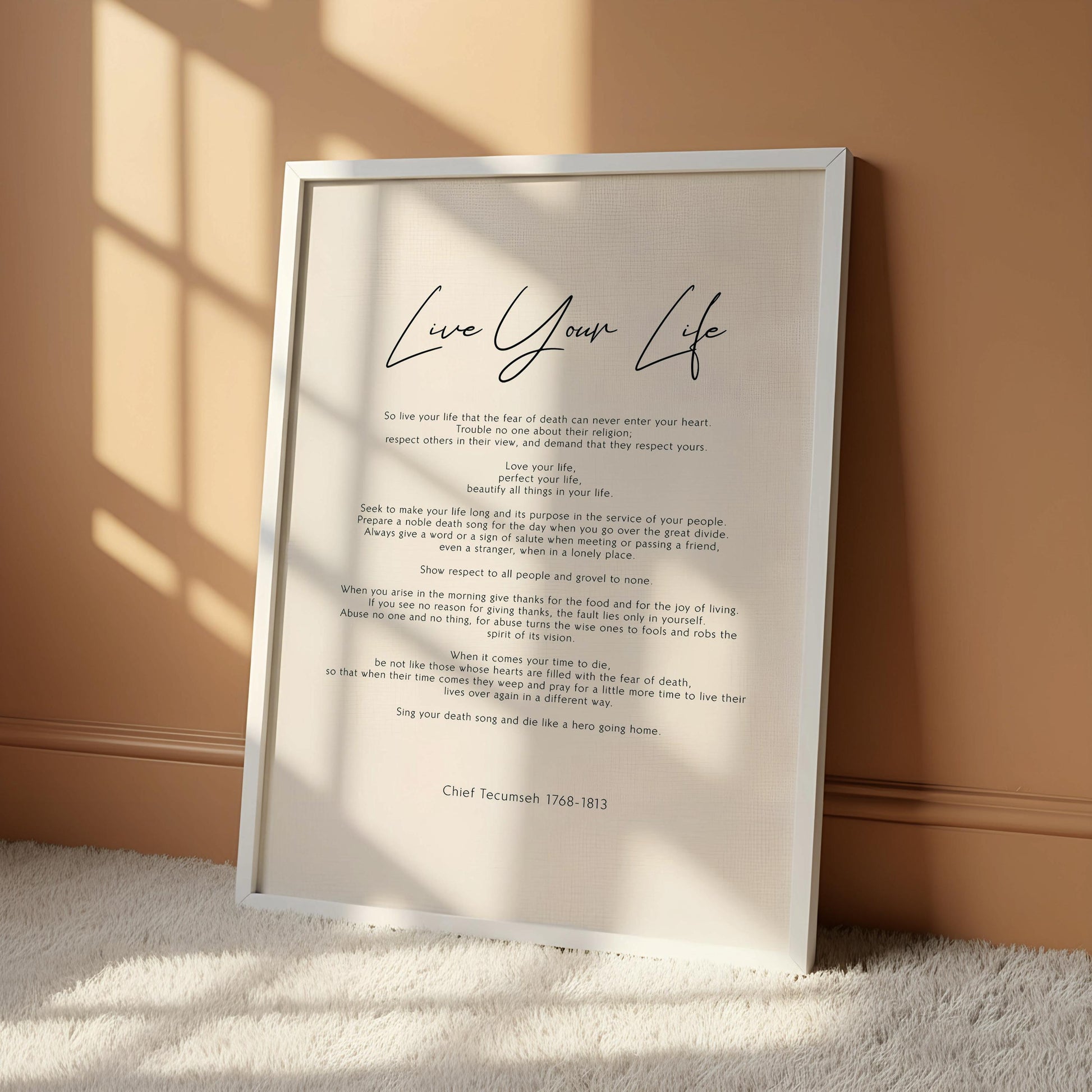 a framed text that reads "Live Your Life" in a cursive font. The text is written in a black and white color scheme and is hung on a white wall.