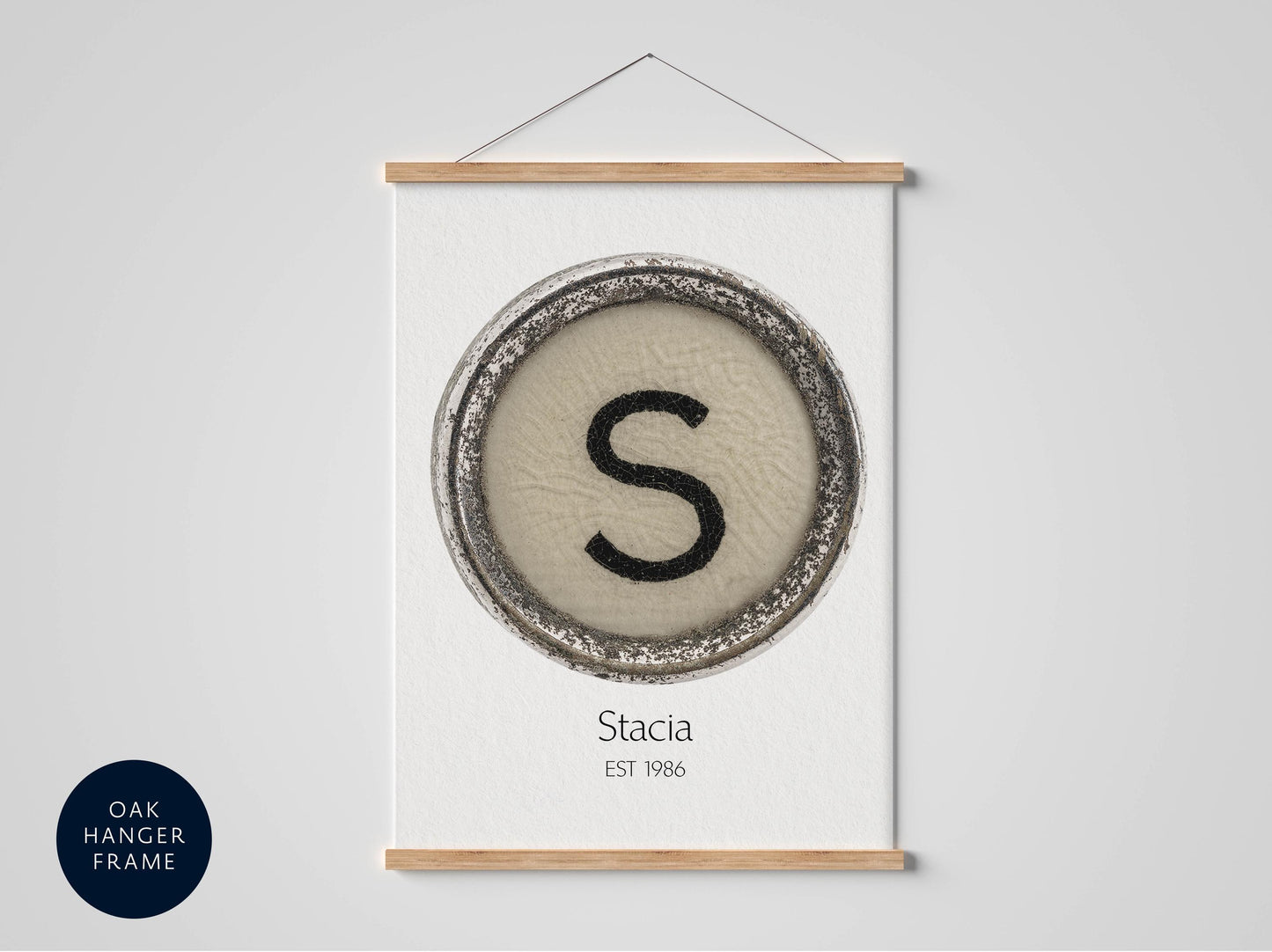 a framed print with a circular design containing the letter 'S' in the center, and the text "Stacia EST 1986" below the design.