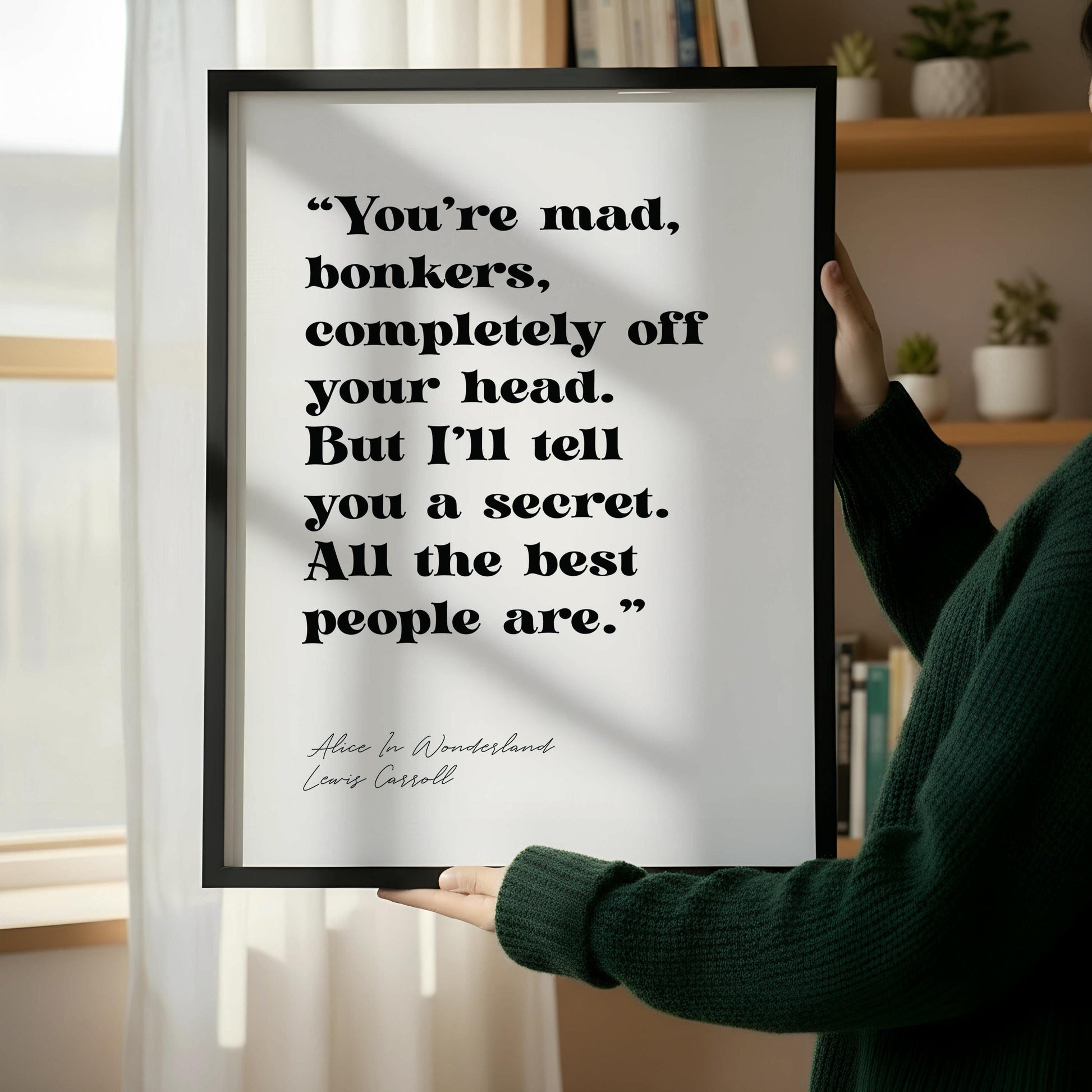 a framed quote on a wall next to a wooden chair, with a book on the chair's seat.