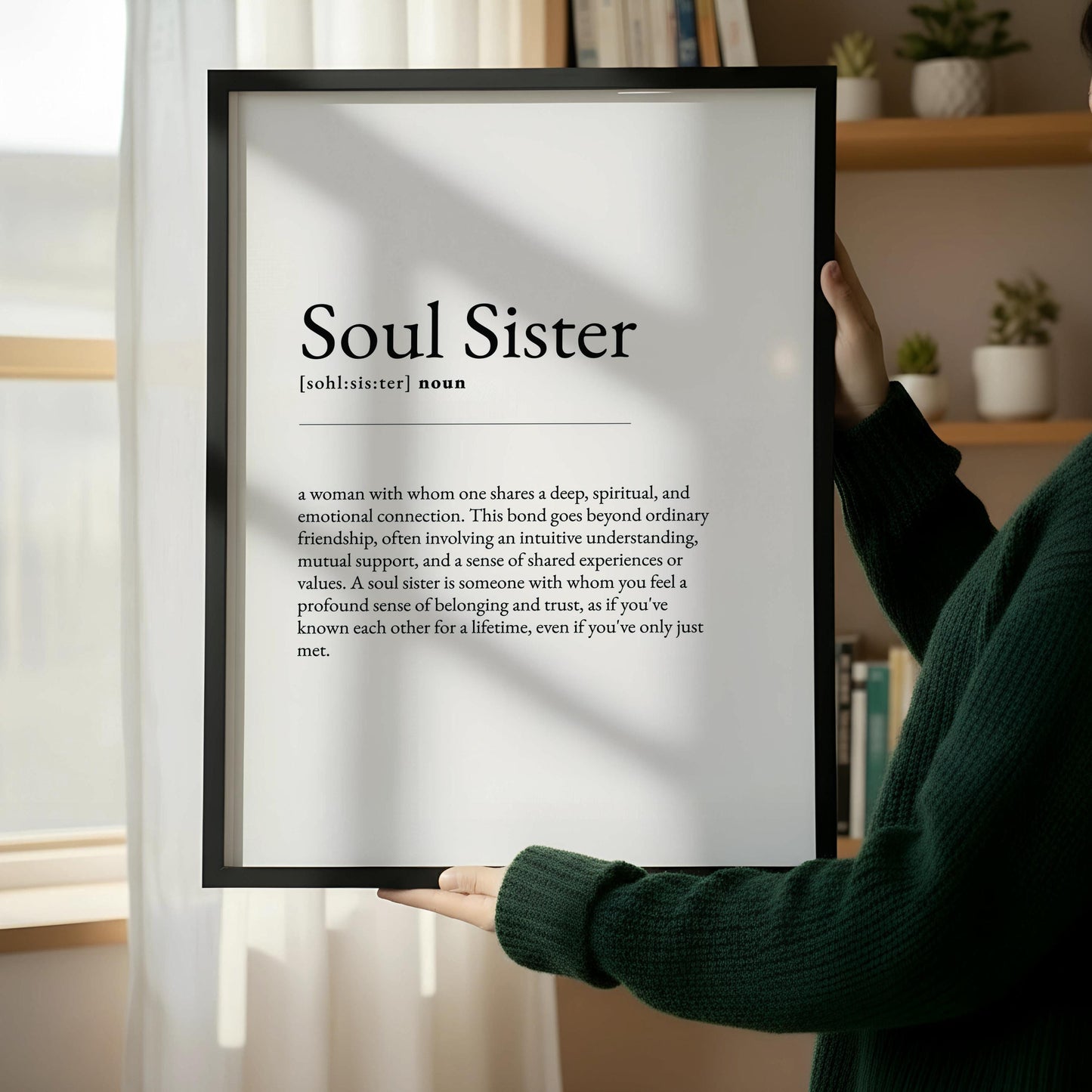 a wooden chair with a book on it, placed against a white wall. There is a framed definition of "Soul Sister" next to the chair.