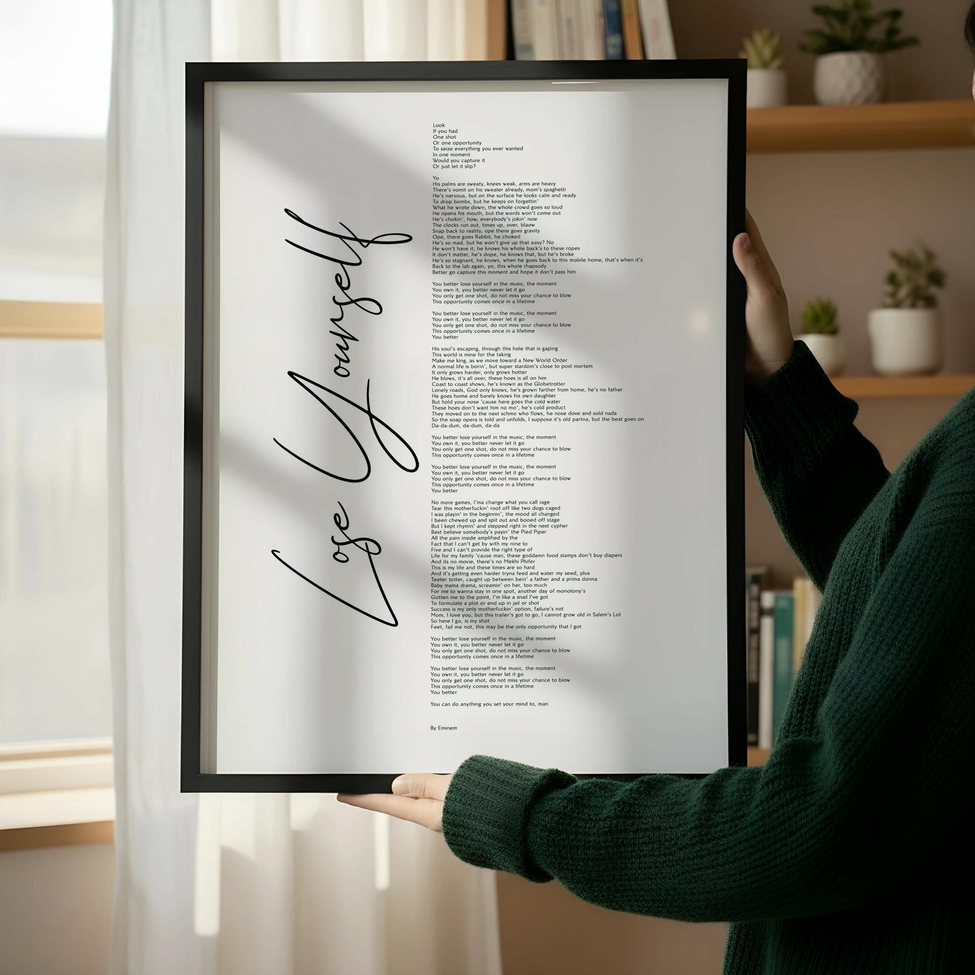 a wooden chair with a book resting on it, and a framed poster with text leaning against a white wall.