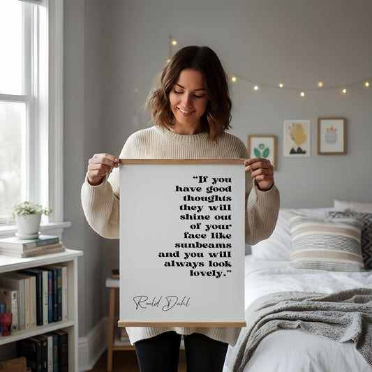 a framed quote by Ralph Dhl on a white wall, accompanied by a desk with a notebook, a cup, and a vase with dried flowers.