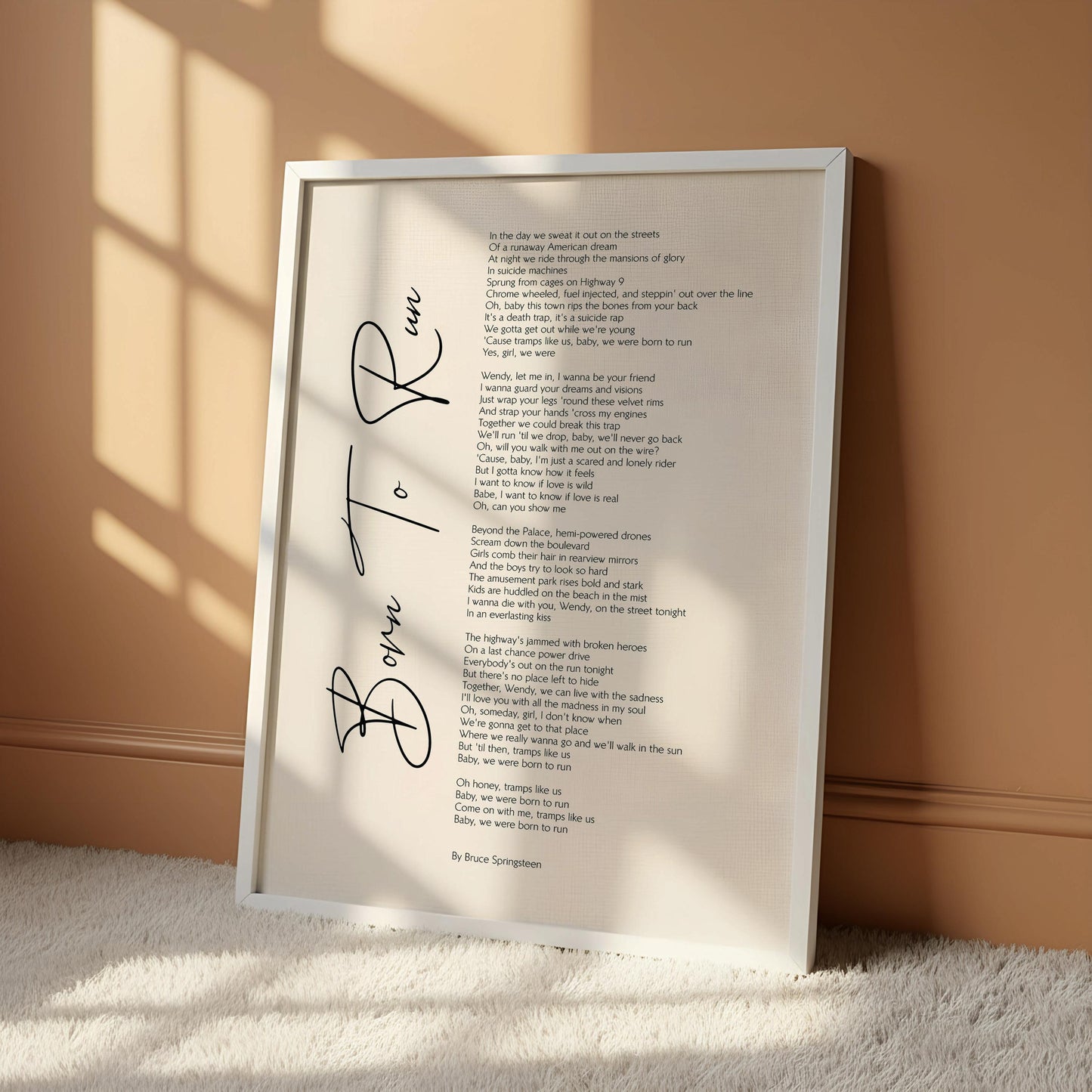 The image is a framed print of a poem titled "Born to Run" by Bruce Springsteen, which is hung on a wall.