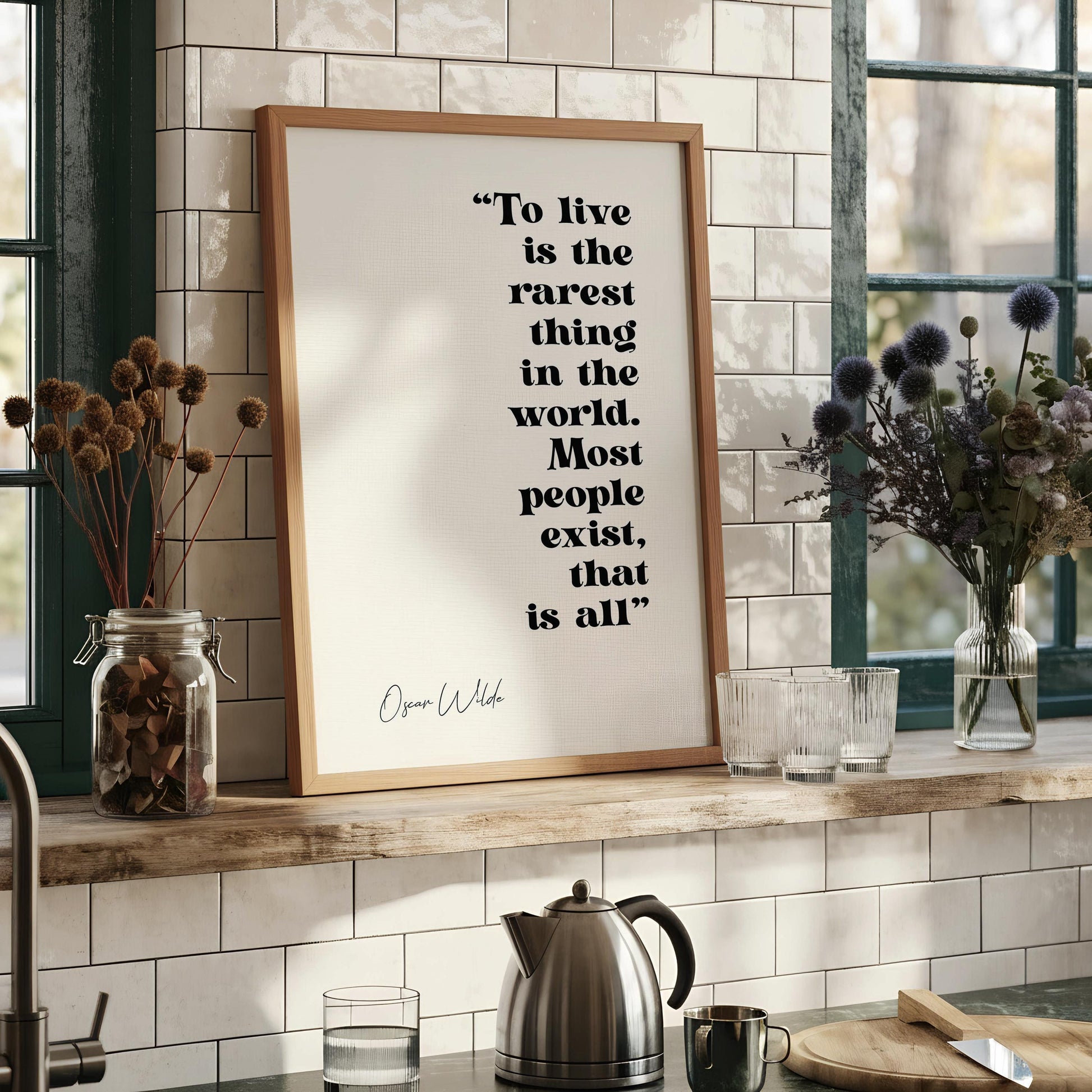 a quote by Oscar Wilde, "To live is the rarest thing in the world. Most people exist, that is all." The quote is displayed in a framed format on a wall.