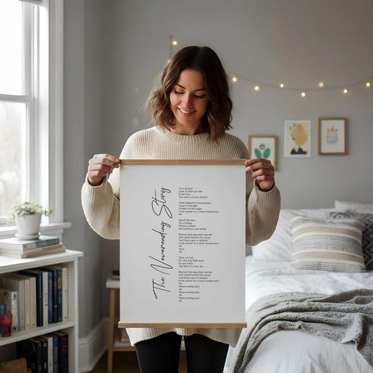 a framed poem titled "The Voice-over Story" displayed on a white desk, accompanied by a notebook, a cup, and a vase with dried flowers.