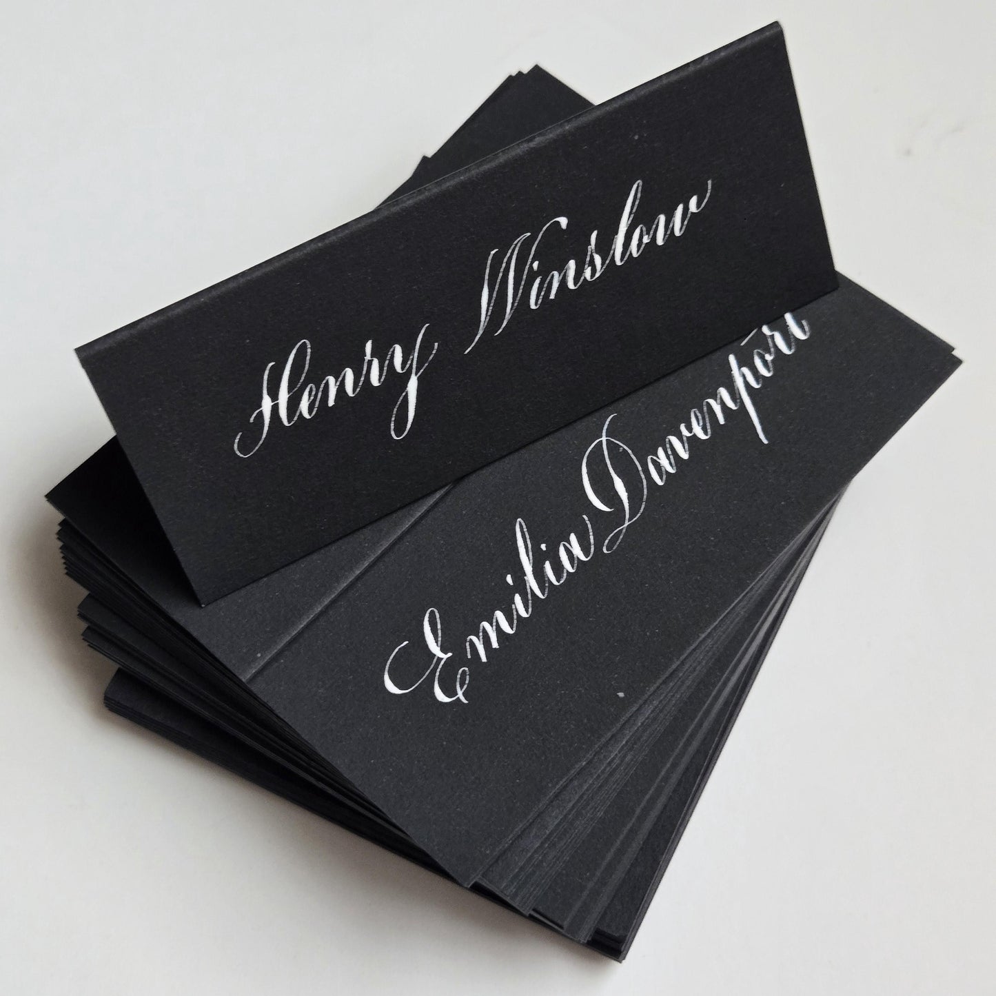 A stack of black name cards with elegant white cursive text.