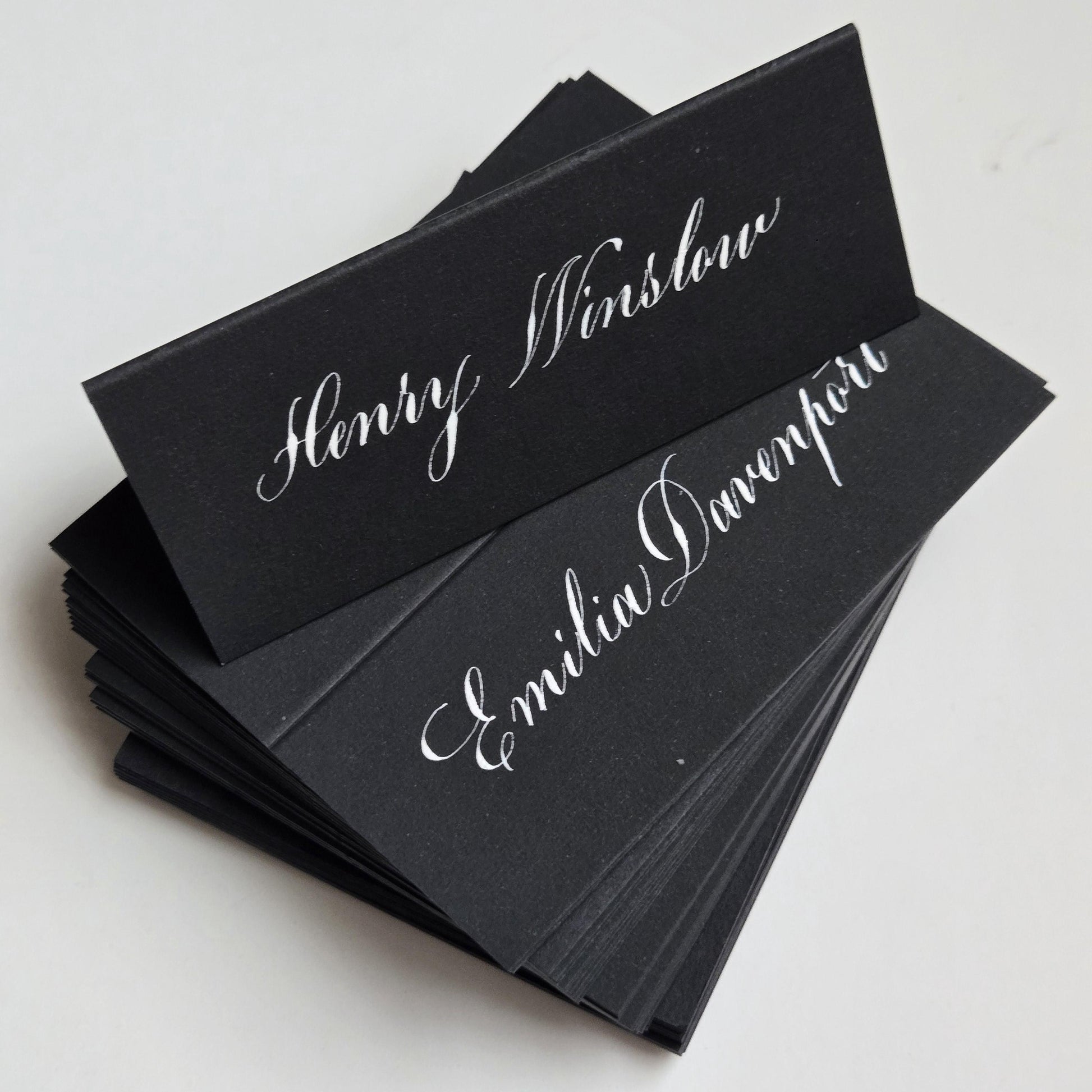 A stack of black name cards with elegant white cursive text.