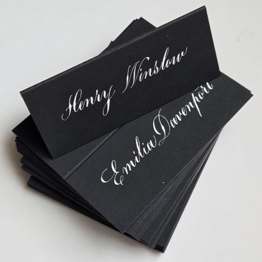 A stack of black name cards with elegant white cursive text.