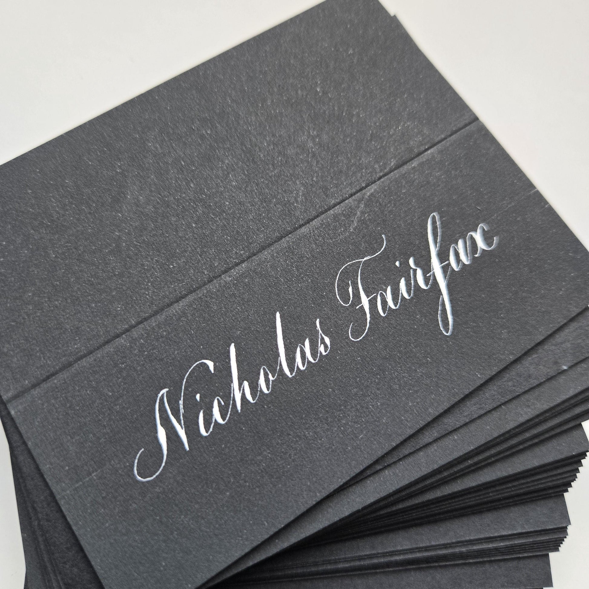 A stack of black business cards with the name "Nikolas Fairface" printed on them.